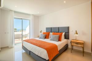 een slaapkamer met een groot bed en een oranje deken bij Orange Beach Ocean View, Porto de Mós VR29 in Lagos