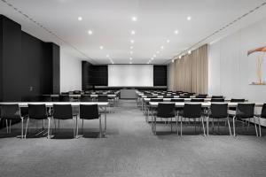a conference room with tables and chairs and a screen at AC Hotel Bologna by Marriott in Bologna