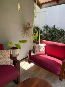 a living room with a red couch and plants at Leel’s Safari Cottage in Udawalawe
