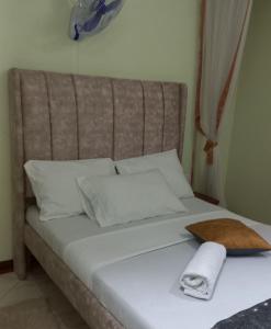 a bed with white pillows and a towel on it at Mtwapa june apartment 2 in Mombasa