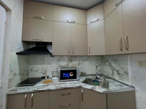 a kitchen with white cabinets and a laptop on a counter at Apart otel sun and moon in Batumi
