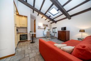 a living room with a red couch and a kitchen at Historic Elegance - Apt in the Heart of Udine in Udine
