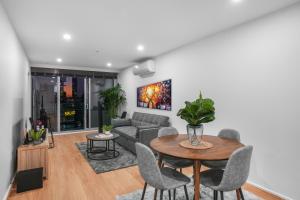 メルボルンにある37th Floor City Views Luxury Apartment and Parkingのソファとテーブルと椅子のあるリビングルーム