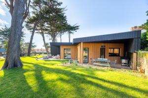 una casa con techo negro y un patio verde en La Cabane des Vagues à Préfailles, en Préfailles