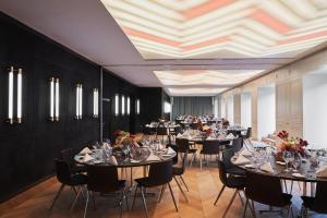 a dining room with tables and chairs with flowers at The Dean Munich, Autograph Collection in Munich