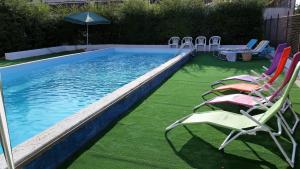 a swimming pool with lawn chairs and an umbrella at B&B Casa Silingardi in Bagnolo San Vito