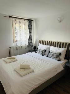 a bedroom with a large white bed with two towels on it at CasaMaria in Slănic-Moldova
