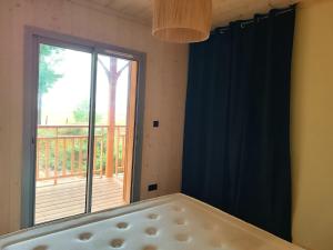 a bedroom with a large window and a balcony at Maison en bois sur pilotis- 4218 in Le Verdon-sur-Mer