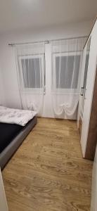 a bedroom with two windows and a wooden floor at Stan Banja Luka Paprikovac in Banja Luka