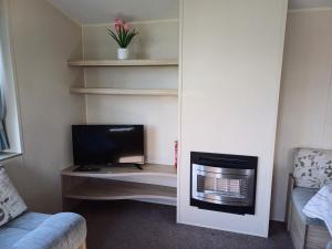 a living room with a tv and a desk with a computer at 3 Bedroom Caravan - Sleeps 8 Parking Pets Beach in Hastings