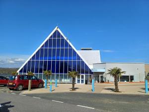 a large glass building with a red car parked in front at 3 Bedroom Caravan - Sleeps 8 Parking Pets Beach in Hastings