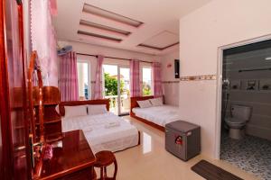 a bedroom with two beds and a desk and a toilet at Khách sạn Thảo Lợi in Con Dao