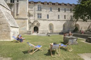 people sitting in lawn chairs in front of a castle at Les Chambres de l'Abbaye in Saintes