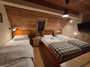two beds in a room with wooden walls at Apartman 304 - Aparthotel Vucko in Jahorina