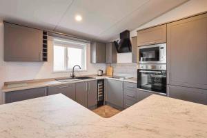 a kitchen with gray cabinets and a marble counter top at Host & Stay - Linden Lodge, Ashdown Retreat in Pickering