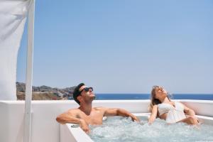 a man and woman sitting in a bath tub on a boat at Volcano Luxury Suites Milos - Adults Only in Paliochori
