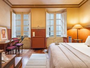 une chambre avec un lit, un bureau et des fenêtres dans l'établissement Casa Indiana en el corazón de Begur, à Begur