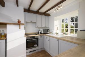 a kitchen with white cabinets and a stove top oven at Beautiful Thatched Cottage in Heart of Dartmoor in Newton Abbot