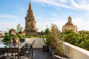 弗洛里亚纳Ellul Living的阳台配有桌椅和钟楼