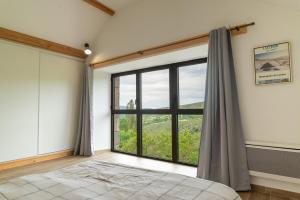 1 dormitorio con ventana grande y cama en La grange d'elie et rosa, en Le Pont-de-Montvert