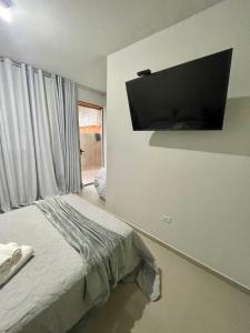 a bedroom with a bed and a flat screen tv on the wall at Caverna Suítes - Suítes na praça matriz in São Thomé das Letras