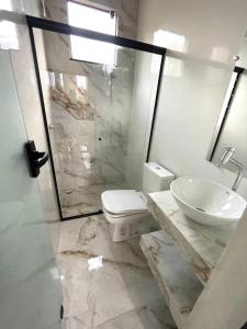 a bathroom with a sink and a toilet and a shower at Caverna Suítes - Suítes na praça matriz in São Thomé das Letras
