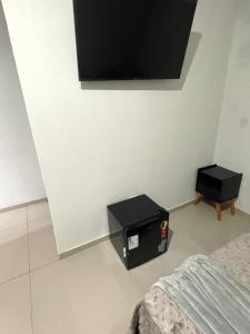 a bedroom with a bed and a tv on the wall at Caverna Suítes - Suítes na praça matriz in São Thomé das Letras +13 photos