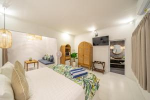 a bedroom with a large white bed and a television at The Hepburn Stylish Single Room Guesthouse with Shared Pool 900m from Seminyak Beach in Seminyak