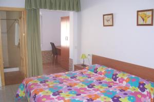 a bedroom with a bed with a colorful comforter at Pensión Nomphosumus in Cala del Moral