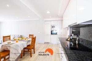 a white kitchen with a table and chairs and a stove at #089 Largo Escola by Home Holidays in Olhos de Água +40 photos