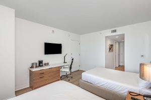 a bedroom with two beds and a desk and a tv at Lovely Studio with Amazing Views in Hallandale Beach