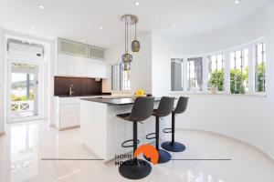a kitchen with white cabinets and black counter stools at #221 Cerro Grande by Home Holidays in Páteo