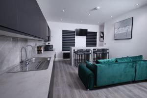 ein Wohnzimmer mit einer grünen Couch und einer Küche in der Unterkunft Spacious 4Bedroom Apartment at Prime Market Street, Watford in Watford