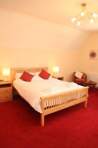 a bedroom with a large bed with white sheets and red carpet at The Red Lion in Revesby