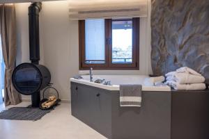 a bathroom with a tub and a window and a sink at Polyzos Luxury Suites Meteora #1 - Adults Friendly in Kalabaka