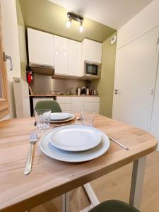 una mesa de madera con un plato blanco en la cocina en Grand studio neuf Bagneux proche transport métro 4 Paris, en Bagneux 5 fotos más