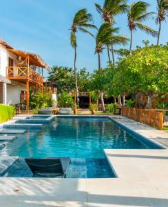 a swimming pool with two chairs and palm trees at Rancharia Charme Beach in Atins