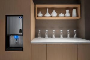 a row of glass vases on a shelf next to a machine at AC Hotel by Marriott Orlando Downtown in Orlando