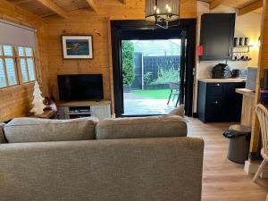 a living room with a couch and a television at Caban Y Tan Dderwen with private Wood Fired Hot Tub in Chwilog