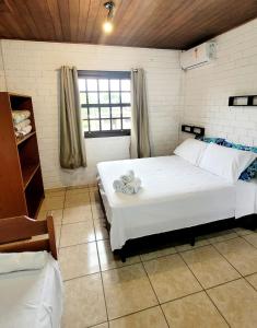 een slaapkamer met een groot wit bed en een raam bij Pousada Uluwatu, Praia do Rosa in Praia do Rosa +33 foto's