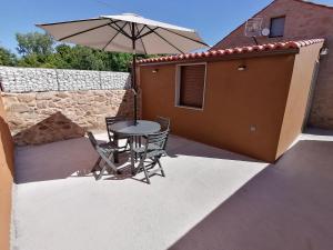 a table and chairs with an umbrella on a patio at Casa da Corna by Cristian&Tamara "alquileres" in Pobra do Caramiñal