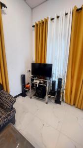 a living room with yellow curtains and a flat screen tv at Pumpkin eco villa in Tangalle
