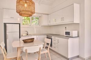 a kitchen with white cabinets and a table with chairs at Villa Hera Periyali in Vasilikos