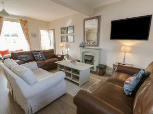 un salon avec des canapés et une télévision à écran plat dans l'établissement Arthur's Cottage, à Dumfries