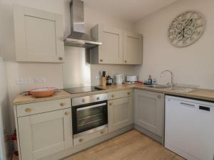 une cuisine avec des armoires blanches et un évier dans l'établissement Arthur's Cottage, à Dumfries