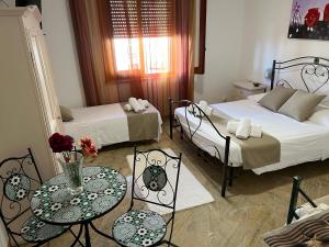 a room with two beds and a table and chairs at Villa Dolce Vita rooms in Castelluzzo