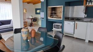 a living room with a glass table and a kitchen at Casa CRETA - Hermenegildo in Santa Vitória do Palmar