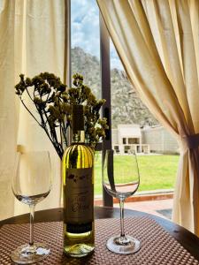 a bottle of wine and two glasses on a table at El Nidito Casa in Chilecito
