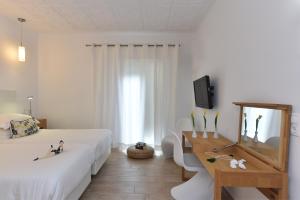 a white bedroom with a bed and a desk and a tv at Apollon Boutique Hotel in Parikia