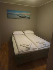a bed with two pillows and a picture of a boat at Tjeldsund Rorbu in Steinsland
